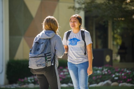 Young woman student wearing an RU First t shirt standing outside on Rockhurst's campus