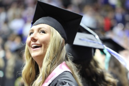 Young woman smiling in cap and gown on graduation day