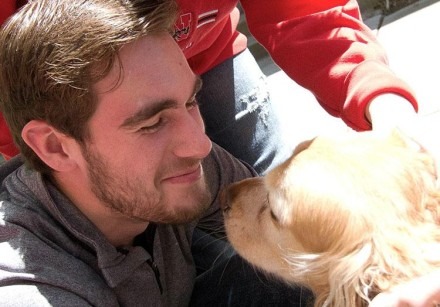 young man cuddling a golden retreiver
